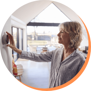 Woman adjusting smart thermostat on wall